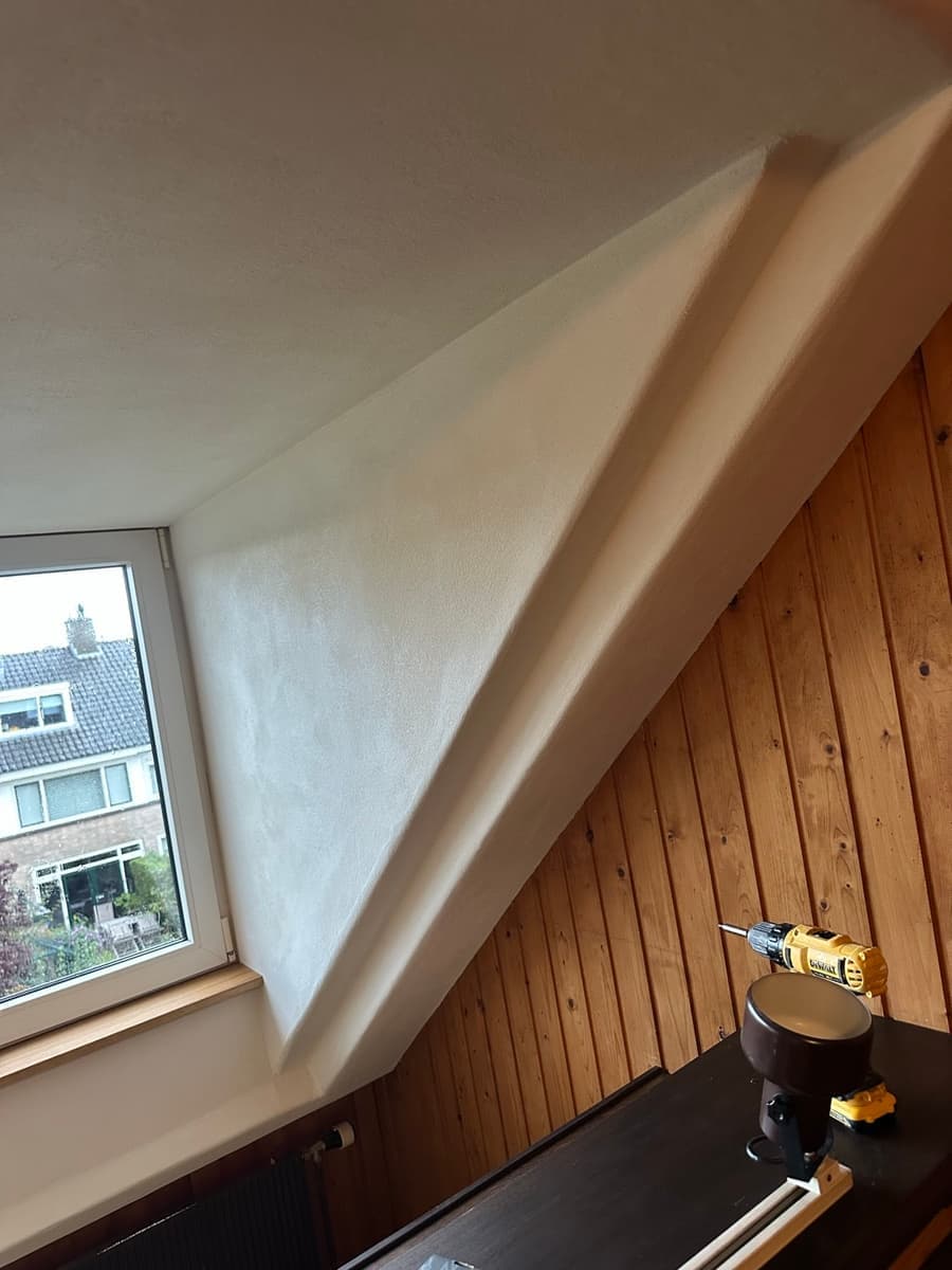 De gestucte wang van de dakkapel, met een rechte lijn langs het houten beschot